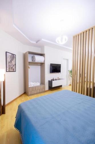 una camera da letto con un letto blu e una televisione di Nikolas House a Vlorë