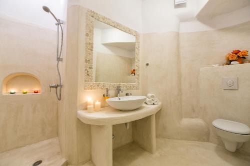 a bathroom with a sink and a toilet and a mirror at Yades - All Sea VIew Suites - Adults only in Naousa