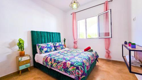 a bedroom with a bed with a green headboard and a window at Great stay at BELLA VISTA CaboNegro in Cabo Negro