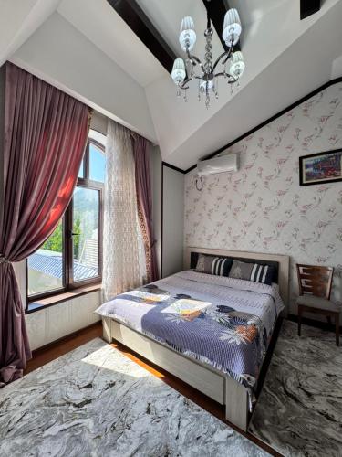 a bedroom with a bed and a window and a chandelier at Dacha Asia in Chorwoq