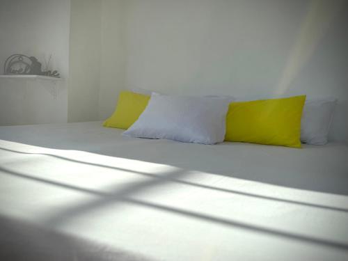 a white bed with two yellow pillows in a room at Apartment in Center of Corozal in Corozal