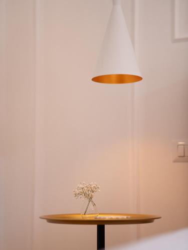 a vase of flowers on a table under a lamp at Maison Odile in Cefalù