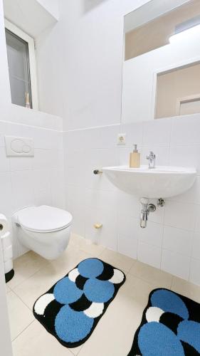 a bathroom with a sink and a toilet and a rug at Spacious Rooms - 15 Min from Airport & City Center, 5 Min from Vienna Main-Bus Station EZ1 in Vienna