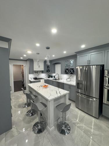 a kitchen with a large island with bar stools at Pearson Gateway Comfort Home in Mississauga