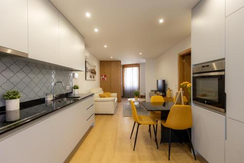 eine Küche und ein Wohnzimmer mit einem Tisch und gelben Stühlen in der Unterkunft Coruja’s House AL OPO in Porto