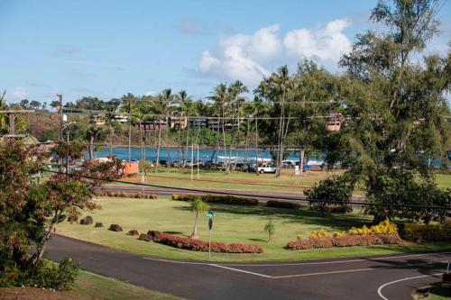 a park with a road and trees and a body of water at Kauai Banyan Harbor B24 by Coldwell Banker Island Vacations in Lihue