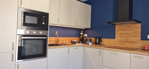 La cuisine est équipée de placards blancs et d'un four micro-ondes noir. dans l'établissement SUPERBE APPARTEMENT porte de la Cité Médiévale entièrement rénové très bien équipé 6 pers balcon clim parking privé devant, à Sommières