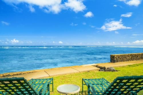 two chairs and a table with the ocean in the background at Kauai Aliomanu Sunrise Hale by Coldwell Banker Island Vacations in Anahola