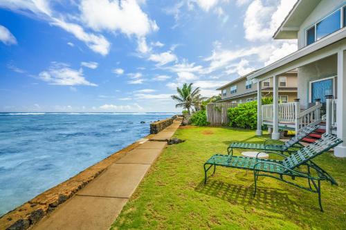a house with two benches on the lawn next to the ocean at Kauai Aliomanu Sunrise Hale by Coldwell Banker Island Vacations in Anahola