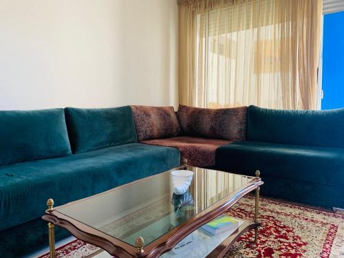 a living room with a blue couch and a glass coffee table at Appart en bord de mer avec piscine vue imprenable in Aourir