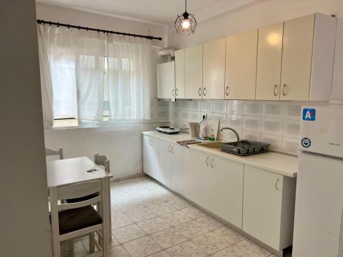 una cucina con mobili bianchi e un frigorifero bianco di PELEKAN rooms and apartments athina 11 a Pefkohori
