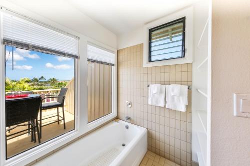 a bathroom with a tub and a window and a balcony at Kauai Manualoha 703 by Coldwell Banker Island Vacations in Kipu