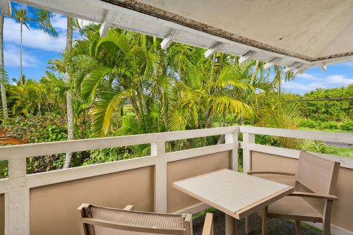 a table and chairs on a balcony with palm trees at Kauai Plantation Hale Suites E12 by Coldwell Banker Island Vacations in Kapaa