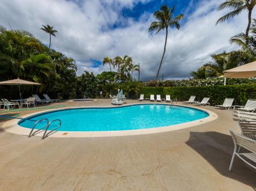 a swimming pool with chairs and palm trees at Kauai Plantation Hale Suites C8 by Coldwell Banker Island Vacations in Kapaa