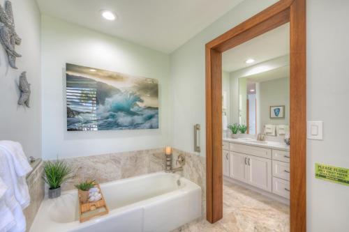 a bathroom with a white tub and a sink at Kauai Poipu Kapili 51 by Coldwell Banker Island Vacations in Kipu