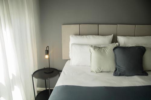 a bedroom with a bed with white pillows and a table at El Misti Suites Buenos Aires in Buenos Aires