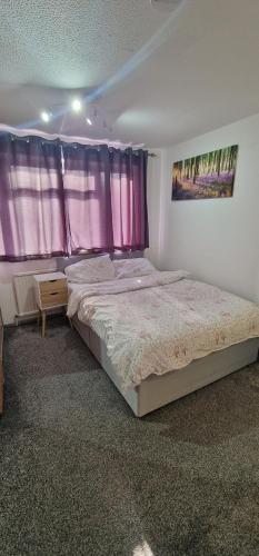 a bedroom with a large bed with pink curtains at Home Away from Home in Dartford