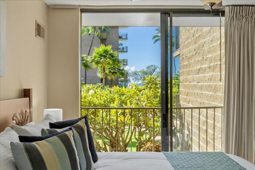 ein Schlafzimmer mit einem Bett und einem großen Fenster in der Unterkunft Kauhale Makai 203 by Coldwell Banker Island Vacations in Kihei