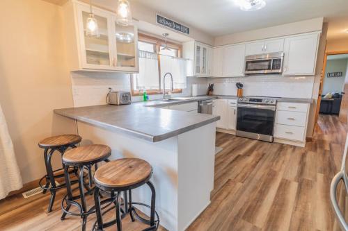 Stadium District Resch 3 BR Sleeps 8 في غرين باي: مطبخ مع خزائن بيضاء وكراسي البار