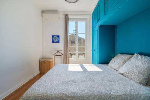 un lit dans une chambre avec un mur bleu dans l'établissement 3 pieces lumineux avec balcon au coeur de la ville, à Nice