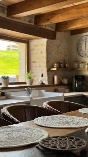 a kitchen with tables and chairs and a clock on the wall at Gîte entier - Alleu des Bois in Oyré