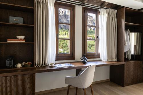 a desk with a chair in a room with windows at Monés in Kastraki