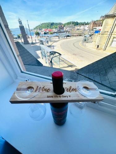 a wooden sign sitting on a window sill with a cup at Kilmartin Court Apartments - No3 By The Sea & No2 With A View - free parking in Oban