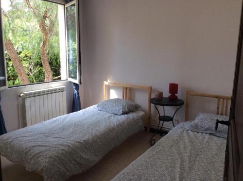 deux lits dans une chambre avec une fenêtre dans l'établissement Villa Mareste, à Grimaud
