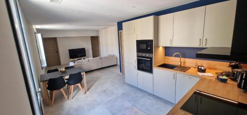 une cuisine avec des armoires blanches et une table et des chaises dans l'établissement SUPERBE APPARTEMENT porte de la Cité Médiévale entièrement rénové très bien équipé 6 pers balcon clim parking privé devant, à Sommières