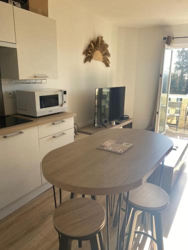 - une cuisine avec une table, des chaises et un four micro-ondes dans l'établissement Appartement duplex climatisé, à Frontignan