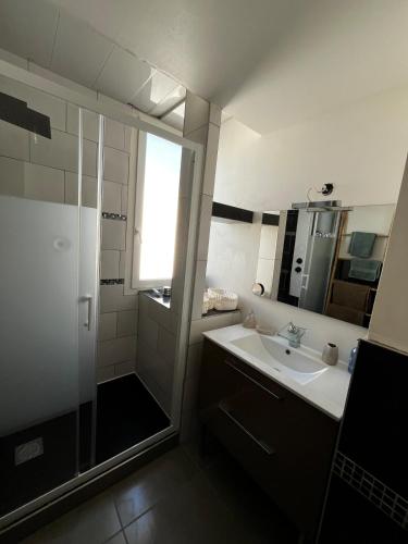 une salle de bain avec une douche, un lavabo et un miroir dans l'établissement Appartement duplex climatisé, à Frontignan