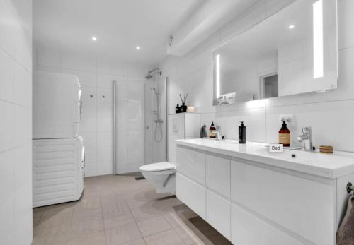 a white bathroom with a toilet and a sink at Large apartment with 4 bedrooms, free Parking, 400m from trainstaion in Lillestrøm