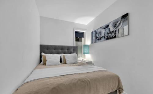 a white bedroom with a large bed with a headboard at Large apartment with 4 bedrooms, free Parking, 400m from trainstaion in Lillestrøm