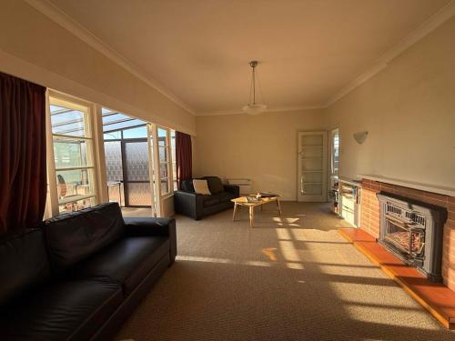 un soggiorno con divano e camino di Sun filled character home a Napier