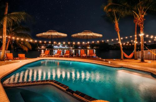 a swimming pool with chairs and umbrellas at night at Waterfront Villa with Beach, Game Room, Cinema and Spa in Pembroke Pines