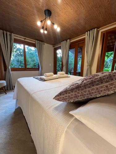 a bedroom with two beds with white sheets and windows at Chalé das Hortências - Parque Nacional do Caparaó in Pedra Menina