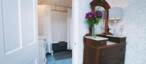 een badkamer met een spiegel en een dressoir met een vaas met bloemen bij The Harrison Inn in Cape May