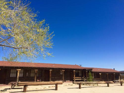 
a park bench in front of a building with trees at Pioneertown Motel in Pioneertown

