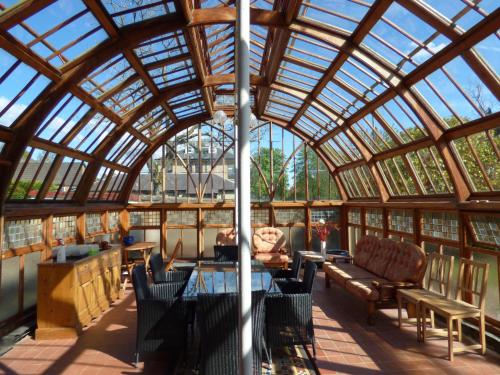 a conservatory with a glass roof with a table and chairs at Moorlands in Helensburgh