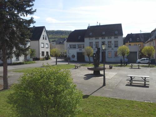 a park with benches and a fountain in front of buildings at Weinhaus Kurtrierer Hof in Leiwen