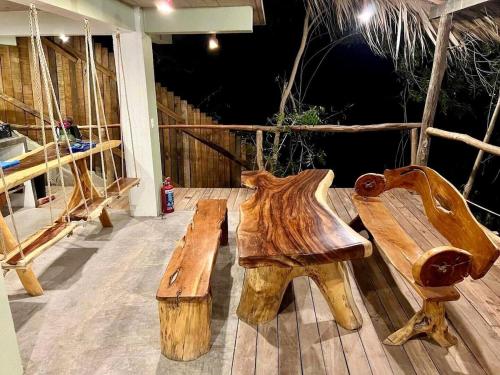 a couple of wooden benches sitting on a deck at Habitaciones en casa De los árboles en la playa con alberca in Arroyo Cruz
