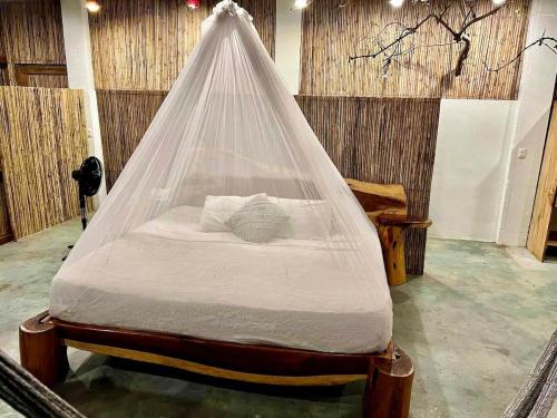 a bed with a net over it in a room at Habitaciones en casa De los árboles en la playa con alberca in Arroyo Cruz