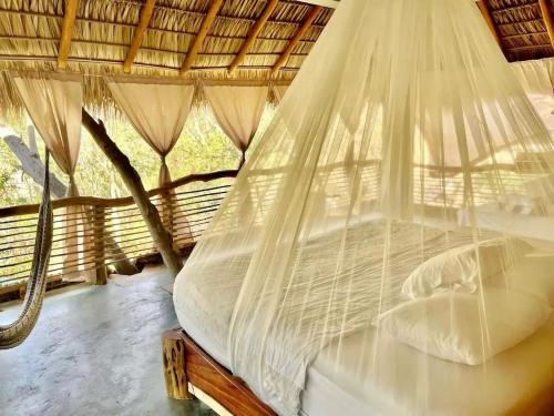 a bed in a room with a net at Habitaciones en casa De los árboles en la playa con alberca in Arroyo Cruz