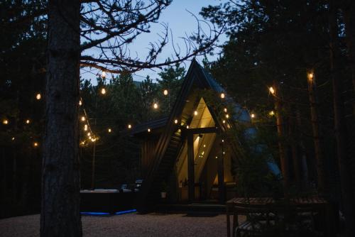 a small cabin in the woods at night with lights at Pinelle Blidinje A-Frame House in Risovac