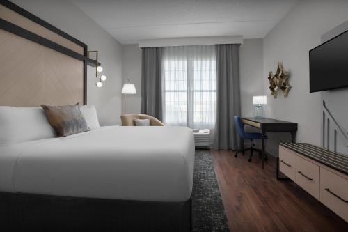 a bedroom with a large white bed and a desk at Hotel Indigo Jacksonville-Deerwood Park by IHG in Jacksonville