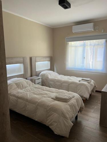 a room with three beds and a window at Dpto Nación in San Nicolás de los Arroyos