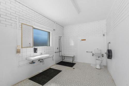 a bathroom with a toilet and a sink and a window at Moss Vale Village Park in Moss Vale
