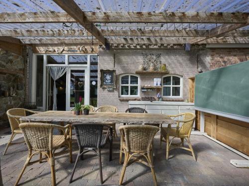 an outdoor kitchen with a wooden table and chairs at Bouwhoeve in Elsendorp