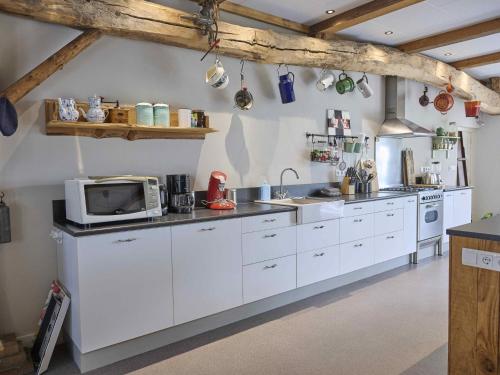 a kitchen with white cabinets and a microwave at Bouwhoeve in Elsendorp