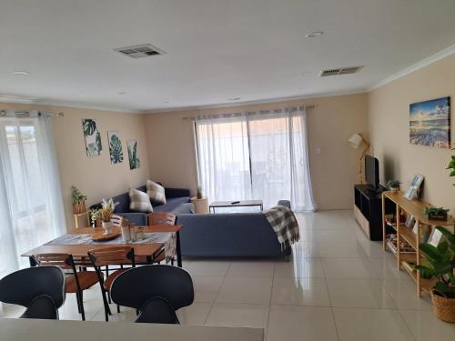 a living room with a blue couch and a table at 5-bedroom 2 bath stylish retreat near beach and wineries in Christie Downs,newly upgraded google TV with Neflix,chromecast, Apple TV, Amazon prime video in Christies Beach